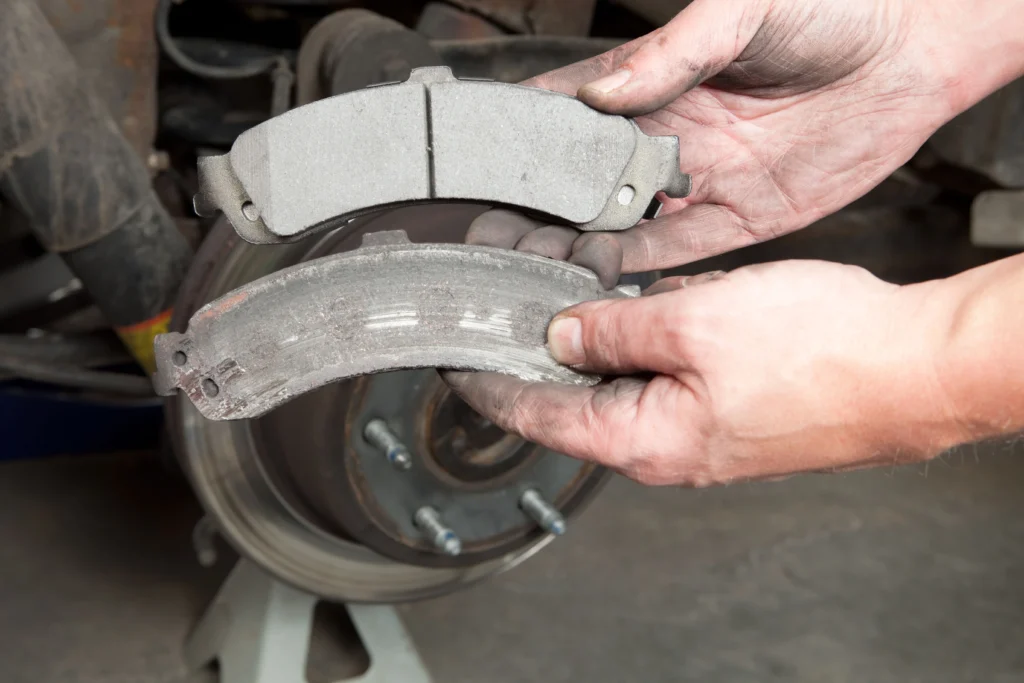 Mechanics Hands Displaying Worn and New Brake Pads x